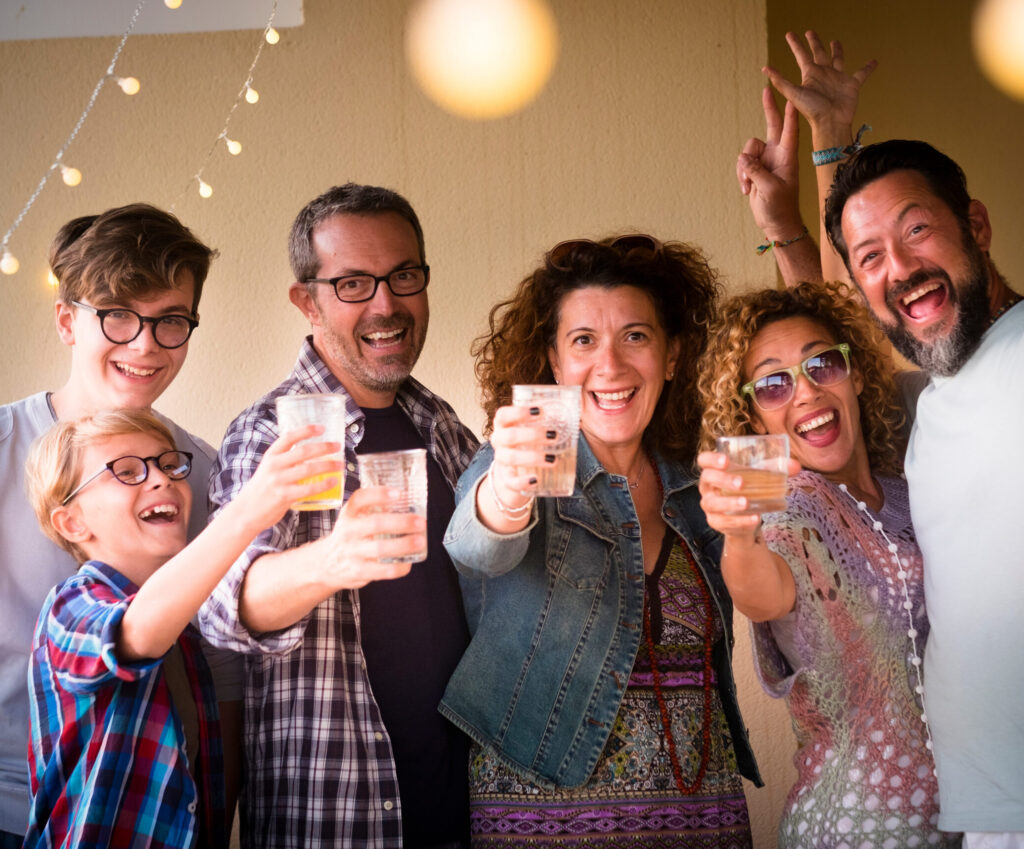 Celebrate people concept with different ages adult and young people toasting all together having fun and laughing a lot - from child to teenager to adult men and women in party event night